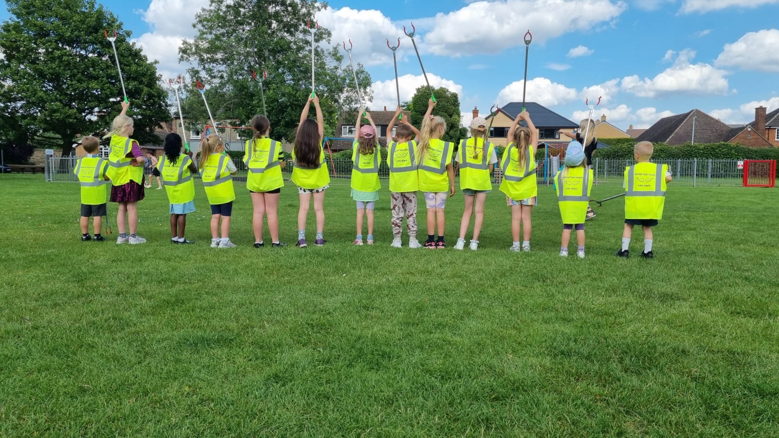 Line of children with 'Litter Angels' vests and litter pickers.